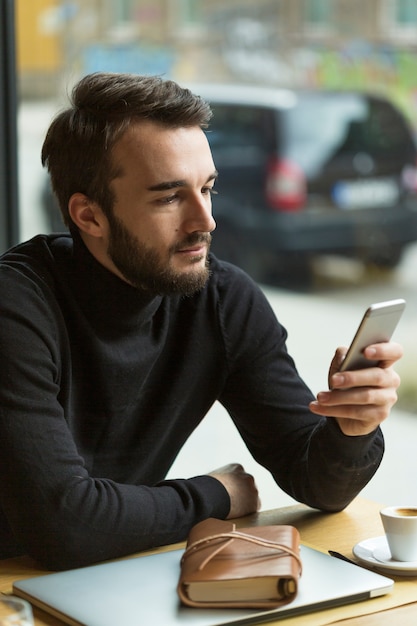 Wysokiego kąta przystojny mężczyzna patrzeje telefon