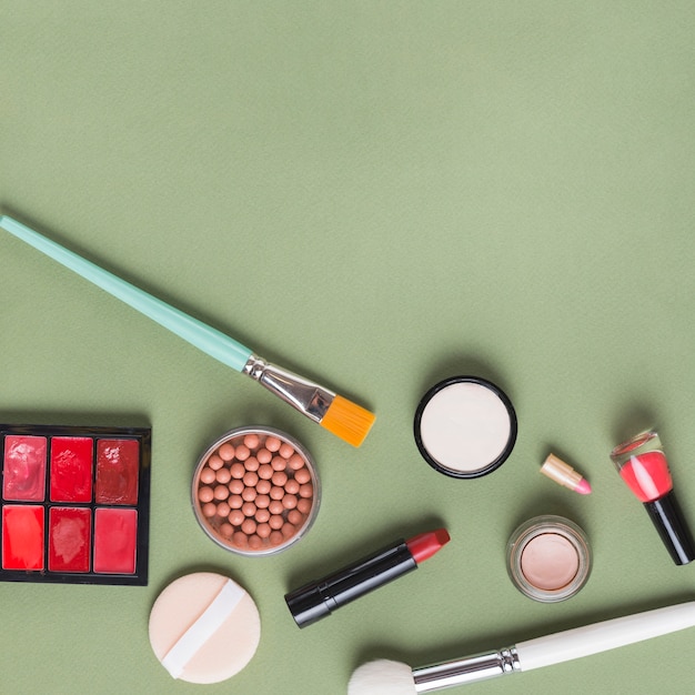 Bezpłatne zdjęcie wysokiego kąta widok różnorodni makeup produkty na zielonym tle