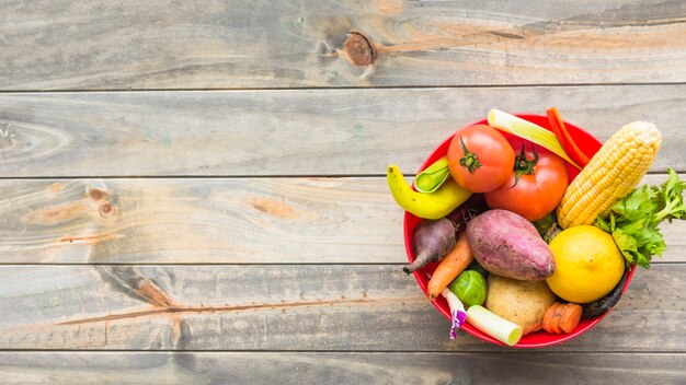 Bezpłatne zdjęcie wysokiego kąta widok zdrowi warzywa w pucharze na drewnianej desce