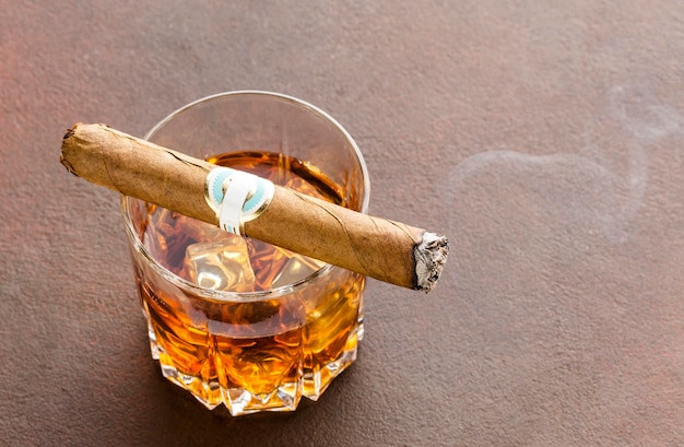 Bezpłatne zdjęcie wysokokątny kieliszek do whisky z lodem i cygarem