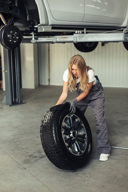 Wysokokątowy żeński mechanik zastępujący koło samochodowe