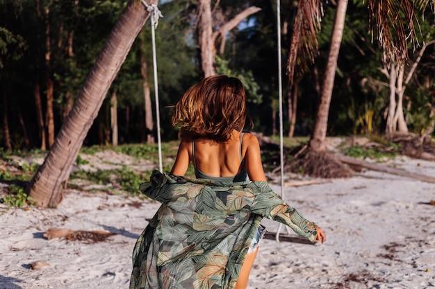 wytatuowana kaukaska kobieta w dżinsowych szortach i zielonym modnym topie na plaży