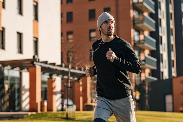 Yung lekkoatletycznego mężczyzna jogging na ulicy podczas słuchania muzyki na słuchawkach.