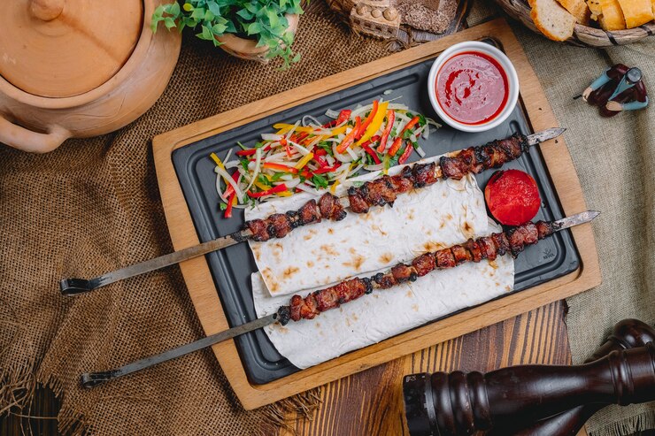 Bezpłatny plik Zdjęcie z góry widok tike kebab na szczypach na chlebie pita z sałatką warzywną i ketchupem
