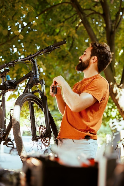 Bezpłatne zdjęcie zaangażowany rowerzysta korzystający z specjalistycznych narzędzi do naprawy i naprawy główki ramy roweru na podwórku sportsloving