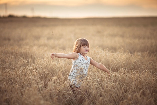 Zabawna dziewczyna tańczy w polu z żytem o zachodzie słońca