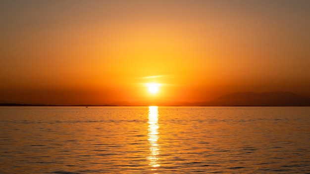 Zachód słońca na wybrzeżu Morza Egejskiego, statek i ląd w oddali, woda, Grecja