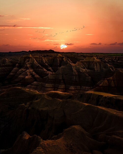 Zachód słońca nad badlands. teren z pasiastymi formacjami skalnymi