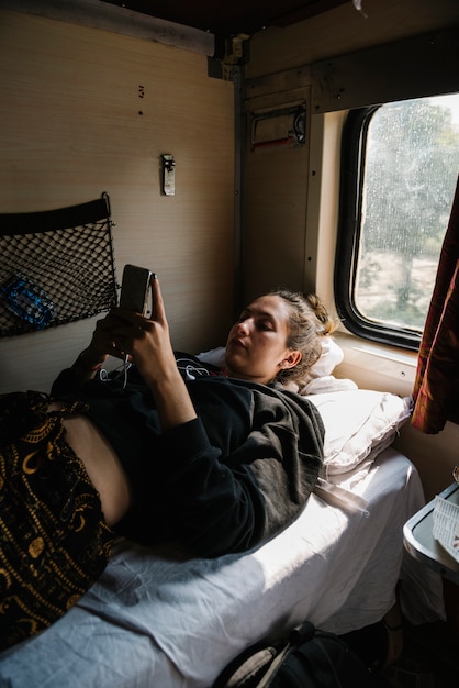 Zachodnia kobieta backpacker używa jej telefon w Indiańskim pociągu