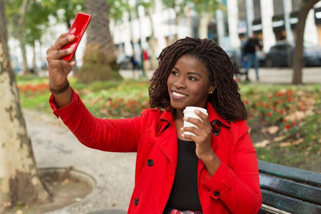 Zadowolona kobieta bierze selfie z smartphone na ulicie