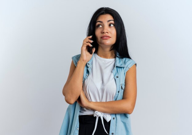 Zadowolona młoda kaukaska kobieta rozmawia przez telefon, patrząc na bok