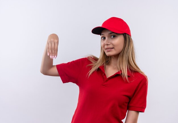 Zadowolona młoda kobieta w czerwonym mundurze i czapce, udająca, że coś trzyma