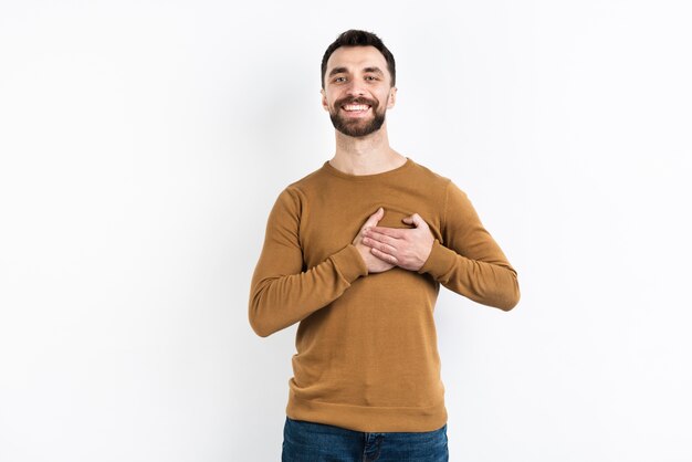Zadowolony mężczyzna pozuje podczas gdy trzymający klatkę piersiową