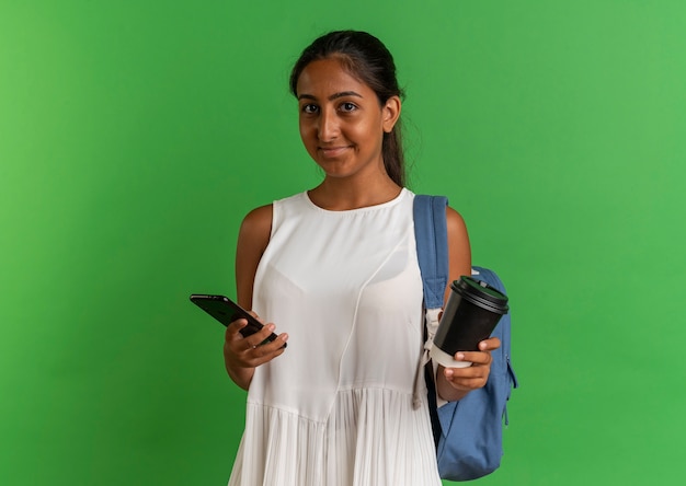 Zadowolony Młoda Uczennica Na Sobie Plecak Trzyma Filiżankę Kawy I Telefon Na Zielonym Tle
