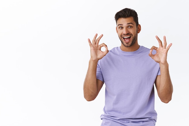 Zadowolony przystojny brodaty milenijny facet w fioletowej koszulce pokazujący dobry gest wyraża zachwycony radość z dobrej koncepcji zatwierdza niesamowity pomysł polecam produkt zostaw pozytywną opinię