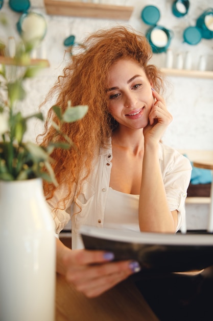 Bezpłatne zdjęcie zadziwiająca piękna rudzielec młoda dama siedzi w kawiarni