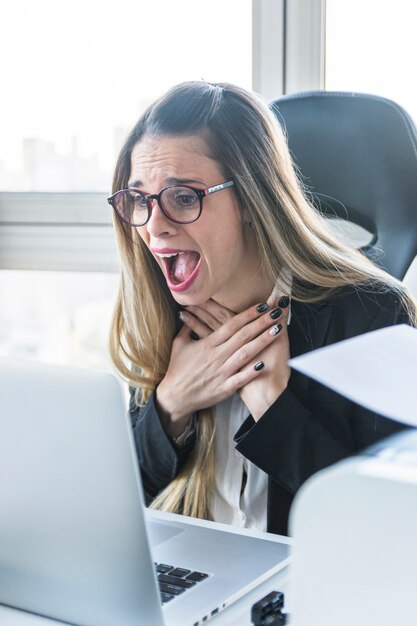 Zadziwiający młody bizneswoman patrzeje laptop