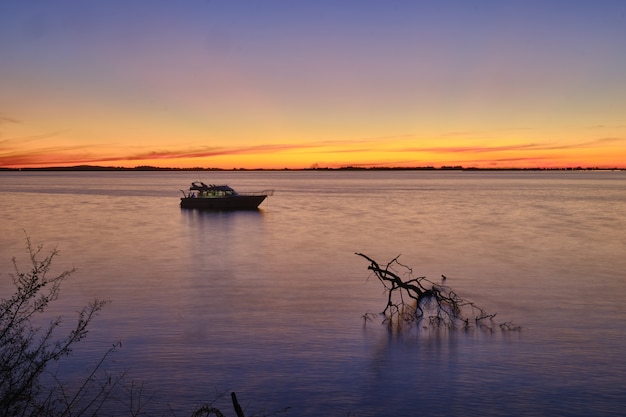 Bezpłatne zdjęcie Żaglówka po spokojnym pięknym oceanie z zapierającym dech w piersiach zachodem słońca