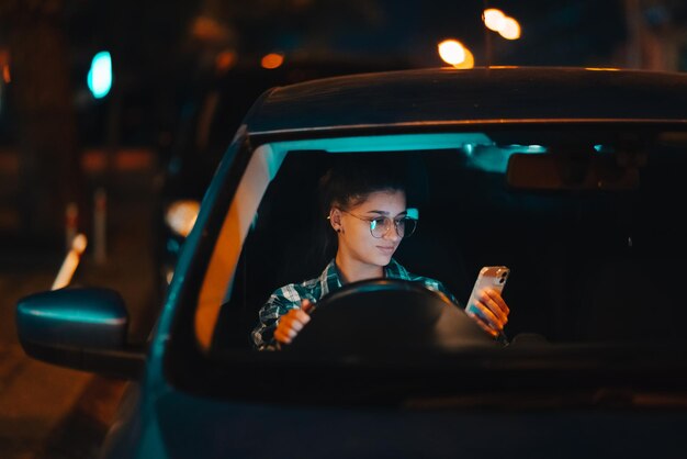 Zagubiona kobieta-kierowca korzystająca z telefonu komórkowego podczas jazdy nocą