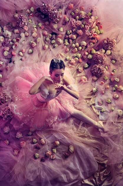 Zakłopotanie. Widok z góry piękna młoda kobieta w różowej spódniczce baletowej otoczonej kwiatami. Wiosenny nastrój i delikatność w koralowym świetle. Koncepcja wiosny, kwitnienia i przebudzenia przyrody.