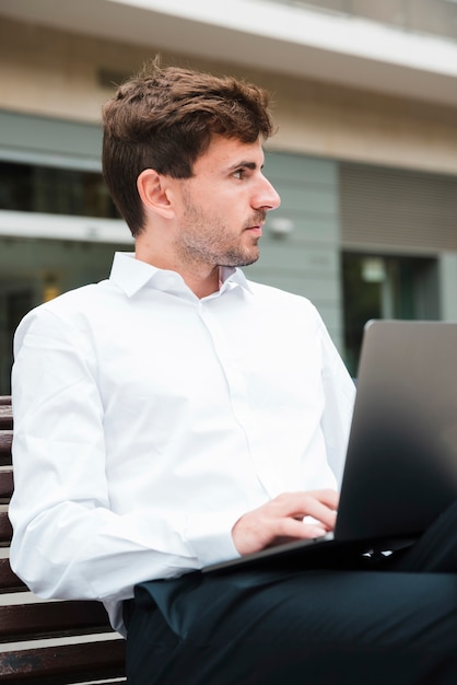 Zakończenie biznesmen używa na laptopie patrzeje daleko od