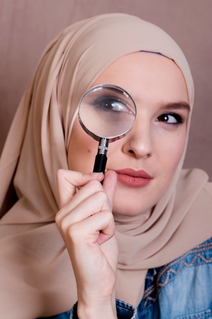 Bezpłatne zdjęcie zakończenie ciekawa muzułmańska kobieta patrzeje przez powiększać