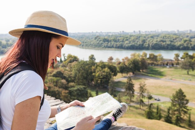 Zakończenie kobieta jest ubranym kapeluszowy patrzeć w mapie przy outdoors