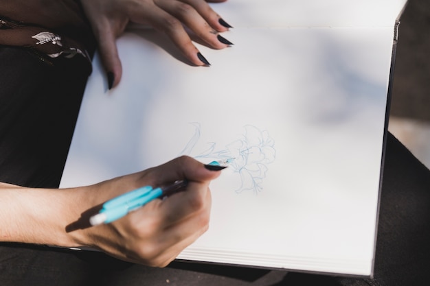 Zakończenie kobieta rysunku kwiat z błękitnym barwionym piórem na notatniku