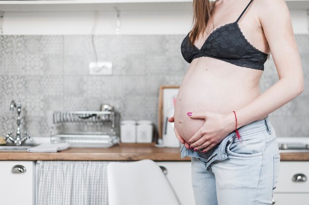 Zakończenie kobieta w ciąży pozycja blisko kuchennego kontuaru trzyma jej brzucha
