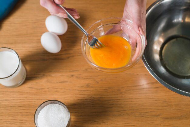 Zakończenie kobiety ręka miesza jajecznego yolk z rozwidleniem w szklanym pucharze