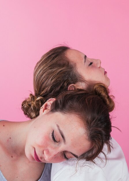 Zakończenie kobiety śpi na each inny ramieniu przeciw różowemu tłu