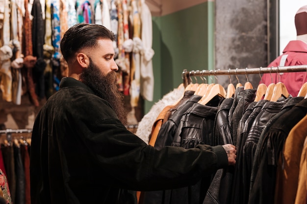 Zakończenie mężczyzna patrzeje skórzaną kurtkę na poręczu w odzieżowym sklepie