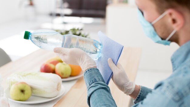 Zakończenie mężczyzna z maskową cleaning bidonem