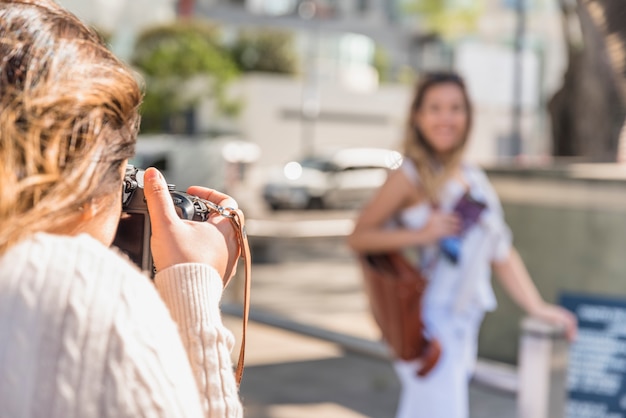 Zakończenie młoda kobieta fotografuje jej żeńskiego przyjaciela z kamerą