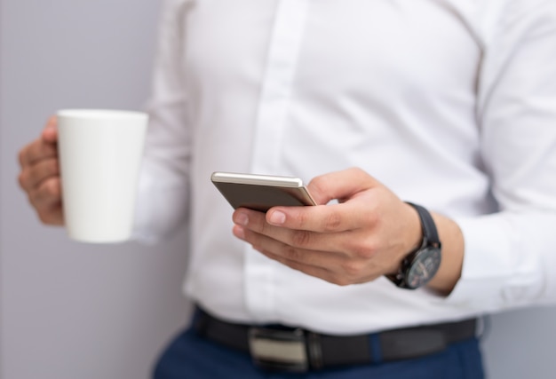 Zakończenie młody biznesmen używa telefon komórkowego indoors