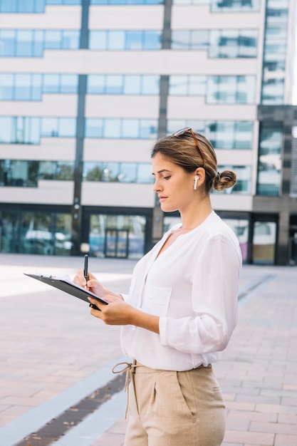 Bezpłatne zdjęcie zakończenie młody bizneswomanu writing z piórem na dokumencie