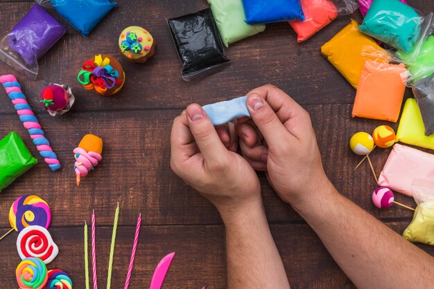 Zakończenie osoba robi tortowi i lollipops z gliną na drewnianym stole