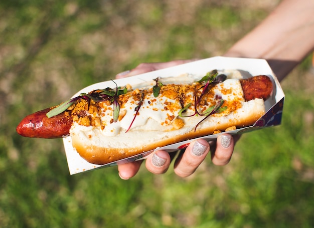 Bezpłatne zdjęcie zakończenie osoba trzyma up smakowitego hot dog