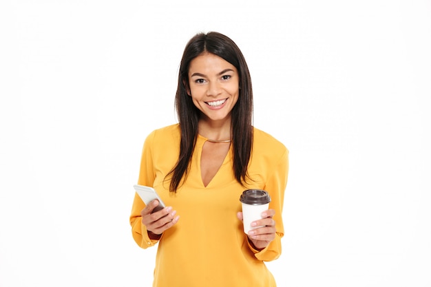 Zakończenie Portret Szczęśliwa Młoda Brunetki Kobieta W żółtej Koszula Trzyma Filiżankę Kawy I Telefon Komórkowego