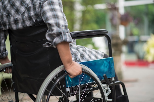 Bezpłatne zdjęcie zakończenie starsza kobiety ręka na kole wózek inwalidzki podczas spaceru w szpitalu