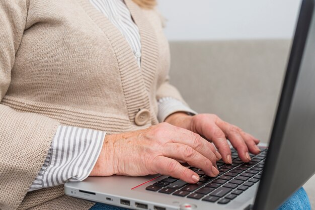 Zakończenie starsza kobiety ręka pisać na maszynie na cyfrowej pastylce