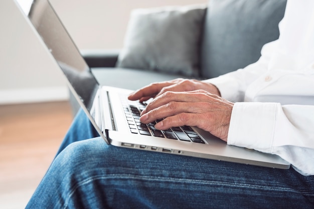 Zakończenie starszy mężczyzna pisać na maszynie na laptopie