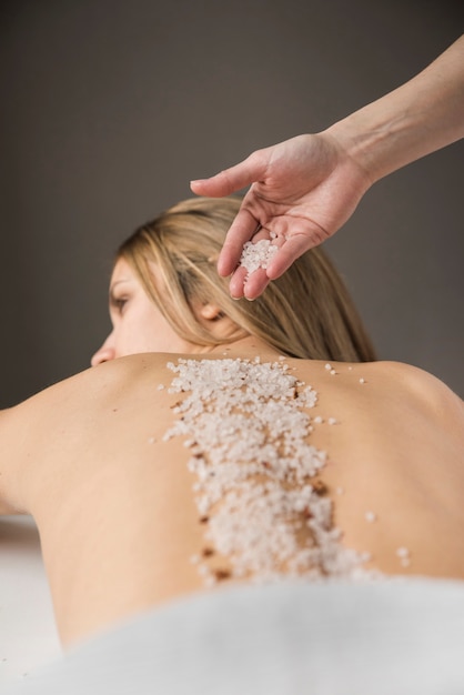 Zakończenie terapeuta ręka stosuje sól na kobieta plecy