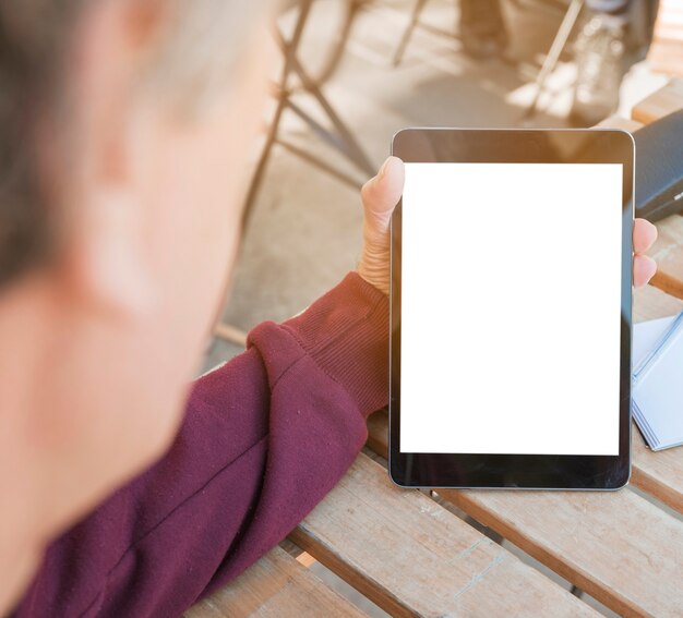 Zakończenie trzyma cyfrową pastylkę z pustym bielu ekranem na drewnianym stole mężczyzna ręka