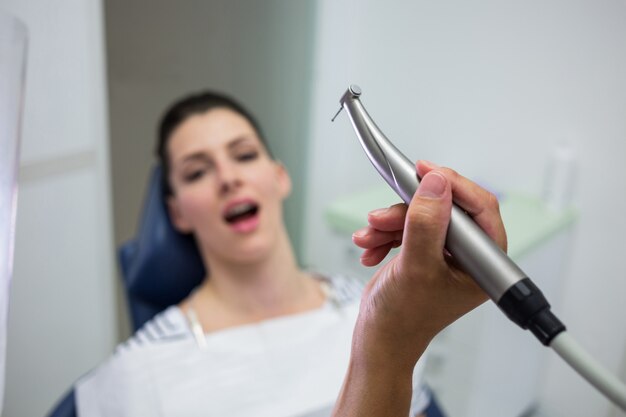 Zakończenie trzyma dentystykę dentysta, stomatologiczny handpiece podczas gdy egzamininujący kobiety