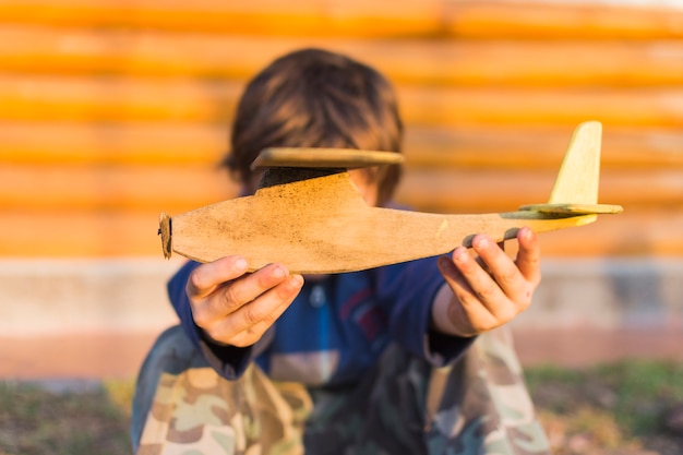 Bezpłatne zdjęcie zakończenie trzyma drewnianego samolot w jego chłopiec chłopiec