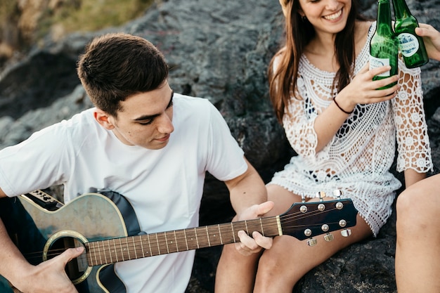 Bezpłatne zdjęcie zakończenie up przyjaciele przy plażą z gitarą