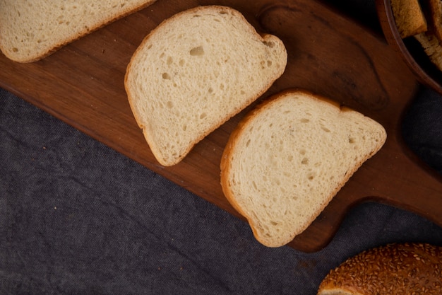 Zakończenie widok białego chleba plasterki na tnącej desce na wałkoniącego się tle z kopii przestrzenią