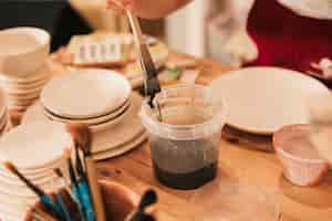 Bezpłatne zdjęcie zakończenie żeński rzemieślnik maluje ceramicznego talerza z pędzlem