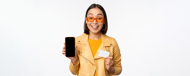 Zakupy online i koncepcja ludzi stylowa azjatycka kobieta pokazująca ekran telefonu komórkowego i kartę kredytową s